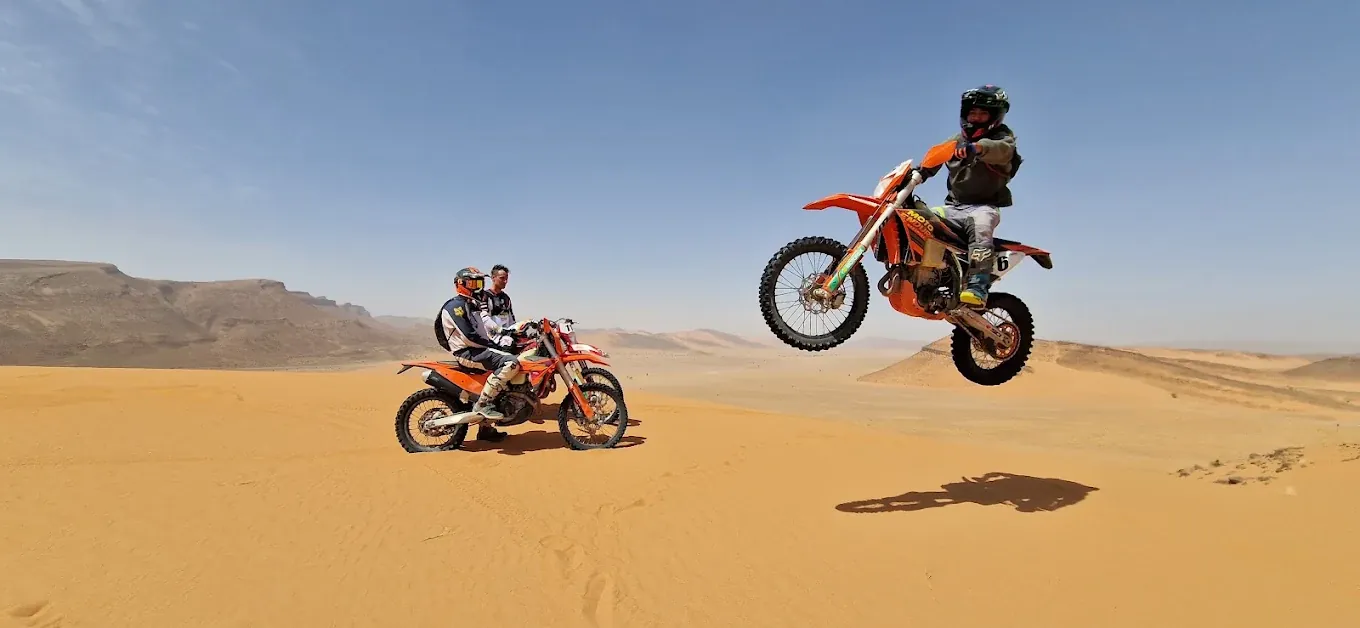 Enduro rider jumping a KTM motorcycle over a Merzouga sand dune Enduro rider crossing Sahara dunes