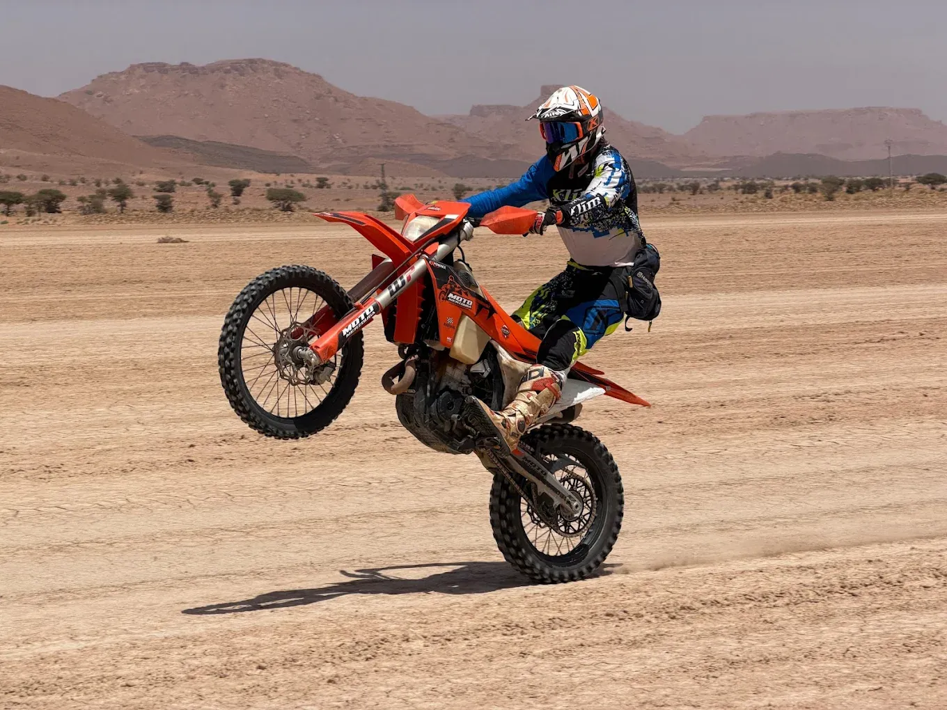 Enduro rider lifting the front wheel on a Morocco desert track Enduro motorcycle in desert terrain: Errachidia — Foum Zguid