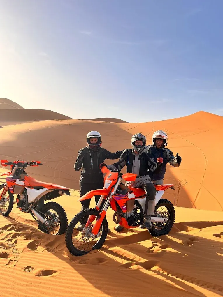 Three Merzouga enduro riders with KTM motorcycles at sunset Rider on the Foum Zguid — Merzouga — Dadès enduro route